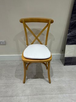 Cross back banqueting chairs with white seat pad.