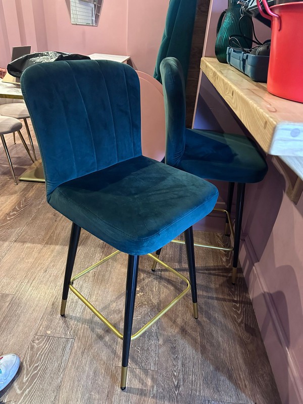 High bar stool in deep green velvet with black and gold legs.